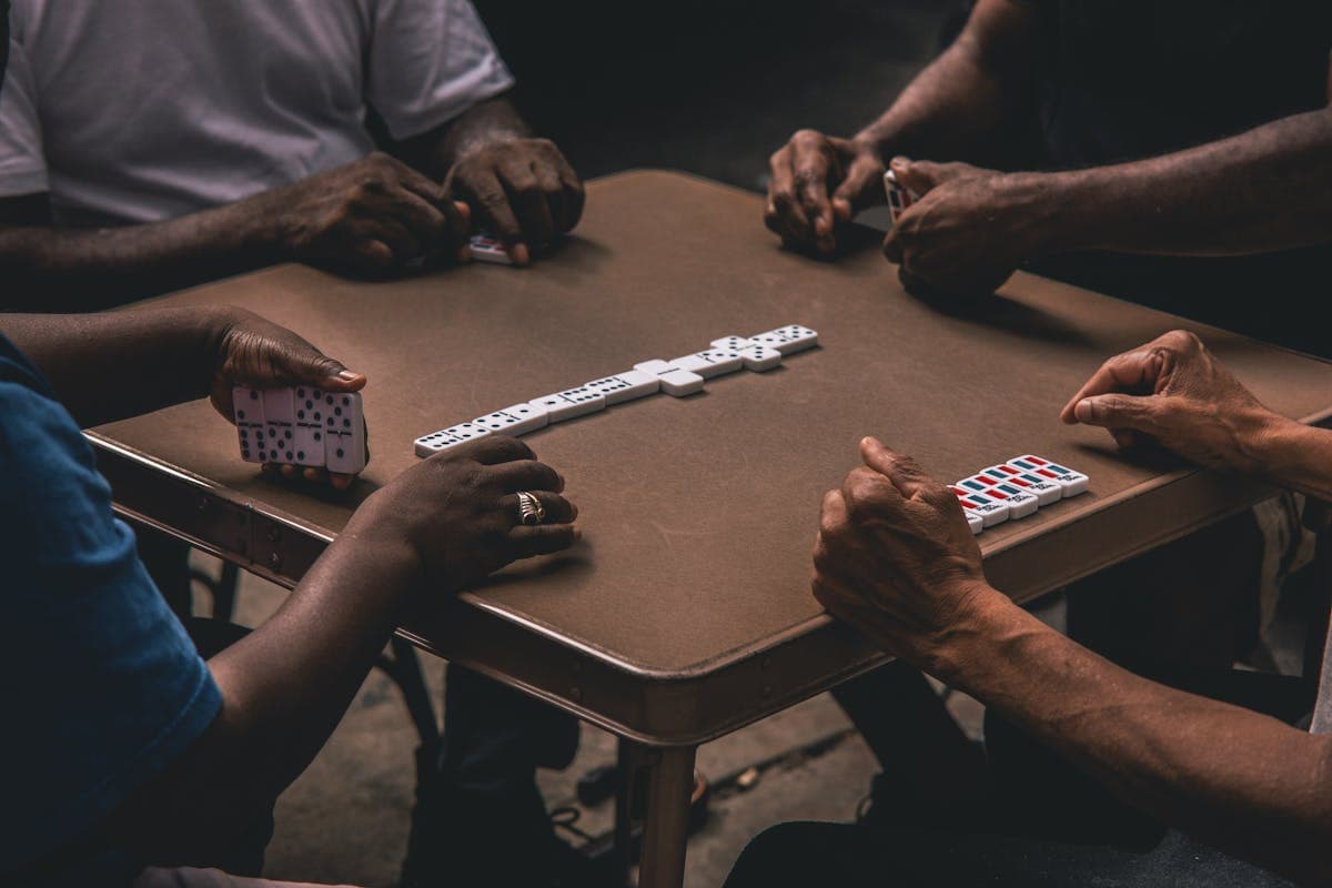 Four men playing dominoes at a proper domino table
